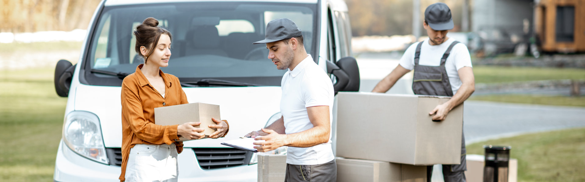 Courier with checklist delivering goods to a young woman by cargo van vehicle